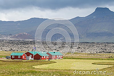 Iceland, 2008, June, Icelandic flag on a filed with traditional houses and a mountain in the background Editorial Stock Photo