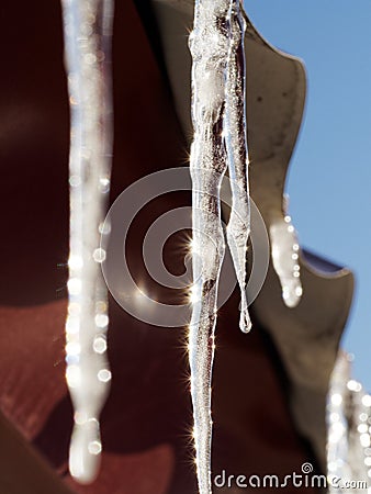 An icicle illuminated by sunlight against the roof Stock Photo