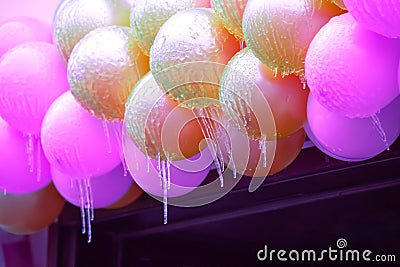 icicles on frozen colored inflatable holiday balls. winter weather season. street interior details Stock Photo