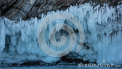 Icicles hang from the base of the rock in several rows, like lace frills Stock Photo