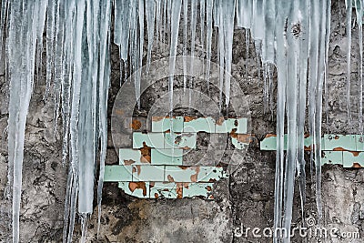 Icicles hanging from the roof of the old brick building with cubes of old tiles, traumatic acrid ice, thaw in the early spring, se Stock Photo