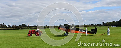 Vintage 1931 Desoutter 1 High Wing aircraft being towed by vintage tractor. Editorial Stock Photo