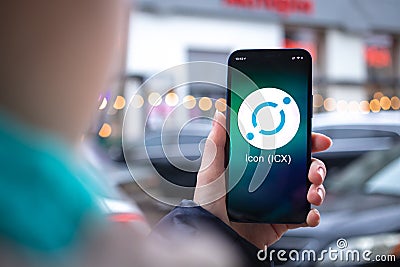 Icon ICX coin symbol. Trade with cryptocurrency, digital and virtual money, mobile banking. Hand with smartphone, screen Editorial Stock Photo