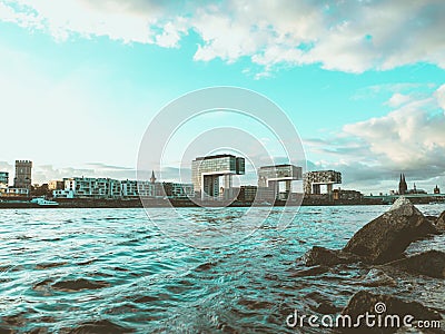 Iconic Crane Houses in Cologne, Germany, with River Rhine and Rocks in Foreground Stock Photo