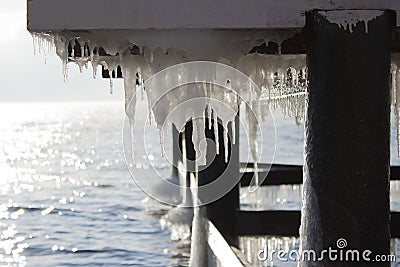 An icy dock for boats. Icicles. Water in the lake. Climate. Baikal in January. Listvyanka. Stock Photo