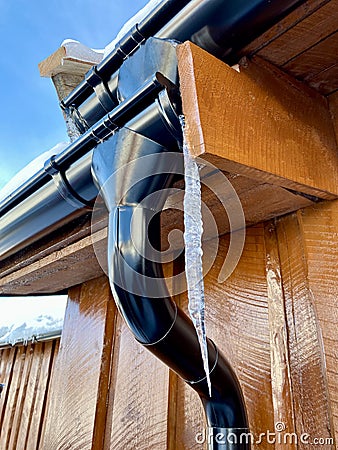 Icycles hanging from guttering on the side of a wooden house. Hovden, Norway, Feb 2023. Stock Photo