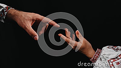 Idea of earth creation. Ukrainian hands reaching out, pointing finger together on black background. Man and woman in Stock Photo