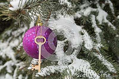 The idea of housing lending, a large lilac ball and the key to the castle on a snow-covered tree, Christmas decorations Stock Photo