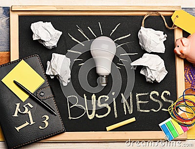 Idea lamp with business accessories on grey chalkboard. Stock Photo