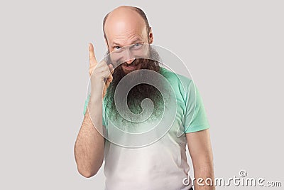 Idea. Portrait of excited middle aged bald man with long beard in t-shirt standing, holding his finger up in idea gesture and Stock Photo