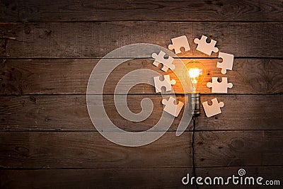 Idea and teamwork business concept, vintage incandescent light bulb and jigsaw on the wooden background Stock Photo