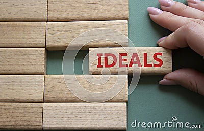 Ideals symbol. Wooden blocks with word Ideals. Businessman hand. Beautiful grey green background. Business and Ideals concept. Stock Photo