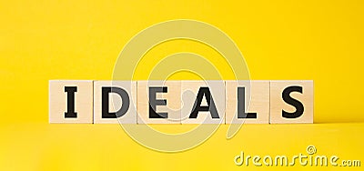 Ideals symbol. Wooden blocks with word Ideals. Beautiful yellow background. Business and Ideals concept. Copy space Stock Photo