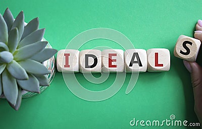 Ideals symbol. Wooden blocks with word Ideals. Businessman hand. Beautiful green background with succulent plant. Business and Stock Photo