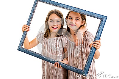 Identical twin girls are making happy expressions with picture frame Stock Photo