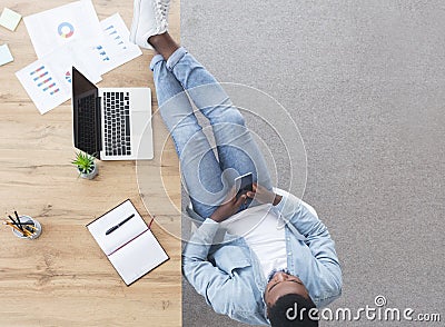 Careless worker using smartphone and keeping his legs on table Stock Photo