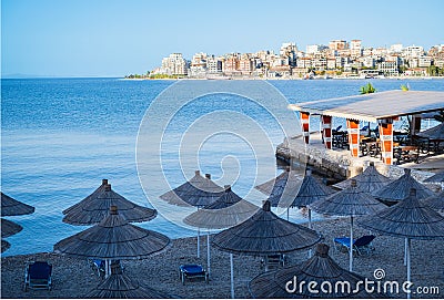 Idyllic beach with restaurant and sun umbrellas in Saranada Albania. Umbrellas on a pebble beach Stock Photo