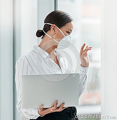 If we cant connect in person lets connect online. a masked young businesswoman holding a laptop and waving out of a Stock Photo
