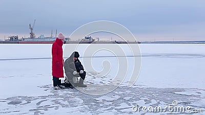 Il pescatore si siede sul pesce congelato dei cathes e del fiume con la canna da pesca dell'inverno di aiuto ed accanto agli orol archivi video Il pescatore si siede sul pesce congelato dei cathes e del fiume con la canna da pesca dell'inverno di aiuto ed accanto agli orol archivi video