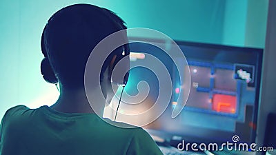 Il ragazzo teenager gioca il gioco online sul computer via il monitor di Internet in cuffie l'uomo dell'adolescente gioca un vide video d archivio Il ragazzo teenager gioca il gioco online sul computer via il monitor di Internet in cuffie l'uomo dell'adolescente gioca un vide video d archivio