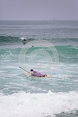 Beach view with professional surfers and Standup Paddleboarding doing extreme maneuvers in sea with waves Editorial Stock Photo