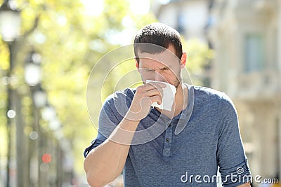 Ill adult man blowing using a tissue in the street Stock Photo