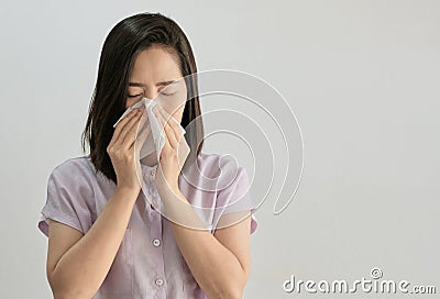 An ill asian woman sneezing, She has a tissue paper in her hands stand on white background. Isolated picture of an ill asian woman Stock Photo