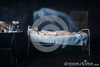 Ill woman lying in hospital bed, soul leaves body Stock Photo