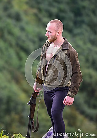 Illegal hunting. Man brutal poacher with weapon natural landscape background. Poaching concept. Poacher stand on edge of Stock Photo