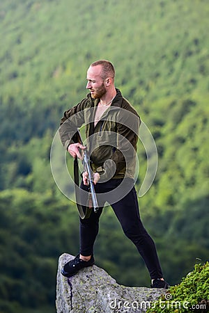 Illegal hunting. Poaching concept. Poacher stand on edge of cliff. Man brutal poacher with weapon natural landscape Stock Photo