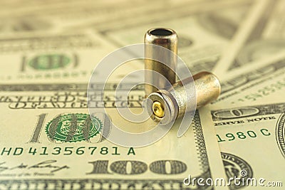 Illegal selling, criminal money concept, US dollars and bullet for a gun, 9mm pistol cartridges on the background Stock Photo