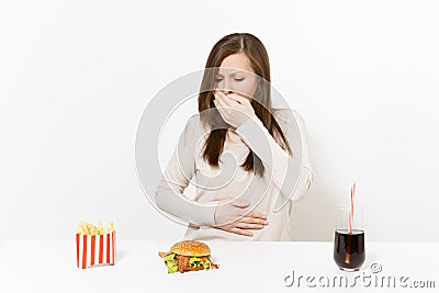Illness woman put hand on pain abdomen, stomach-ache at table with burger, french fries, cola in glass bottle isolated Stock Photo