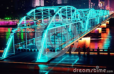 Illuminated bridge on top of a river in a cityscape at night Stock Photo