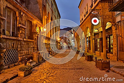 Illuminated cobbled street with light reflections on cobblestones in old historical city by night. Dark blurred Stock Photo