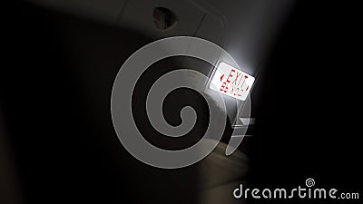 Illuminated Exit sign in dark room. Art. Bright sign indicating Exit glowing red on white background in pitch darkness Stock Photo