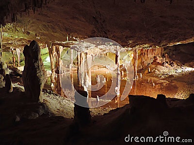 Illuminated lake inside of a dripstone cave. Stock Photo