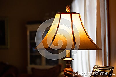 Illuminated lamp with shade in a dimly lit room Stock Photo