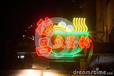 Illuminated neon restaurant sign hanging on a building in Kowloon City at night Editorial Stock Photo