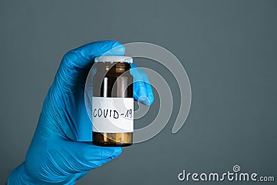 Illuminated photo of Doctor in surgical gloves is holding bottle of drugs medicament, pills and tablets for treatment Covid 19 Stock Photo