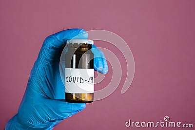 Illuminated photo of Doctor in surgical gloves is holding bottle of drugs medicament, pills and tablets for treatment Covid 19 Stock Photo
