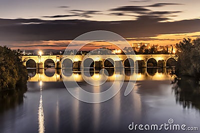 Illuminated Roman bridge over Guadalquivir river at evening in Cordoba, Andalusia, Spain Stock Photo