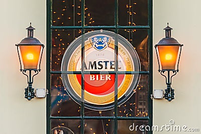 Illuminated sign with the Dutch Amstel Beer logo behind a window Editorial Stock Photo