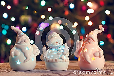 Illuminated Snowman and Jack Frost (Santa Claus) dolls in front of Christmas tree lights, blurred background Stock Photo