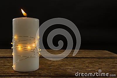 Illuminated string lights wrapped on lit candle Stock Photo