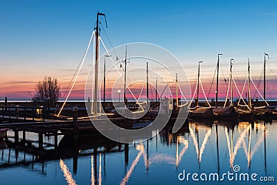 Illuminated traditional wooden fishing ships at night in Dutch harbor Stock Photo