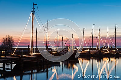 Illuminated traditional wooden fishing ships at night in Dutch harbor Stock Photo