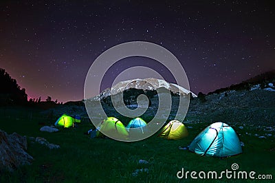 Illuminated yellow camping tent under stars at night Stock Photo