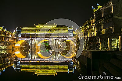 illumination lights decoration of bridge in FengHuang village reflect as a circle on river with traditional chinese houses Editorial Stock Photo