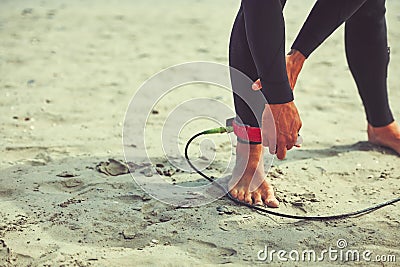 Im attached to surfing. a surfer tying his surfboard leash around his ankle. Stock Photo
