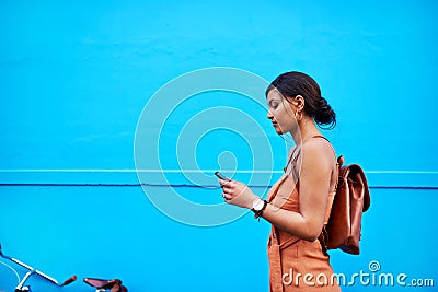 Im connected every step of the way. an attractive young woman using a cellphone while traveling with her bicycle against Stock Photo